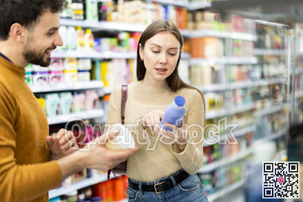 Married couple buyers chooses shampoo or shower gel in household chemicals store