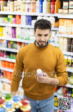 Young man choosing body and hair care products in supermarket
