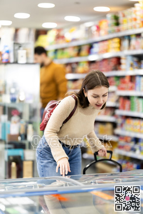 Young woman choosing frozen food in grocery store