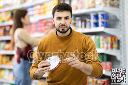 Man in supermarket search and select product tin can