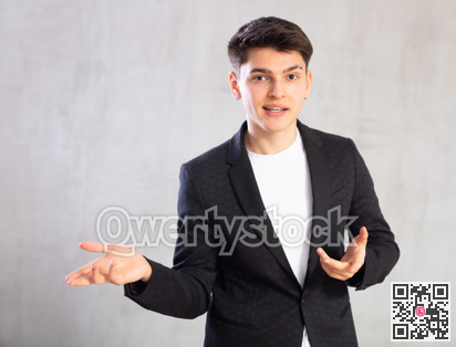 Smiling surprised young male student in suit jacket pointing at you.Portrait of guy pointing finger