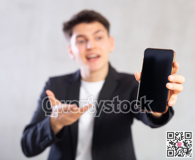 Smiling young guy holding mobile phone in his hand