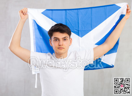 Focused young guy holding flag of Scotland