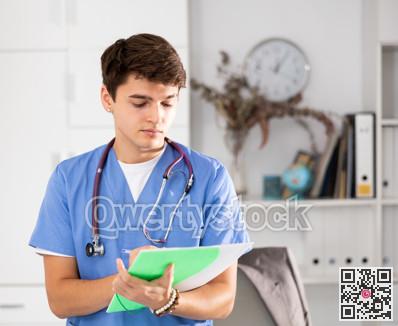 Positive male doctor who works at the clinic writes important notes on folder of documents while