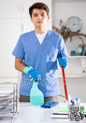 Portrait of positive male cleaner in protective uniform at company office
