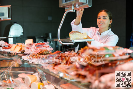 Young woman weighing cheese at counter