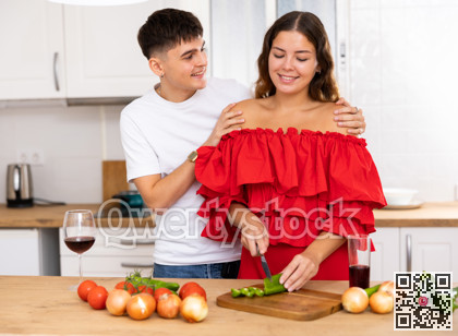Young happy married couple with glasses of wine preparing a festive dinner