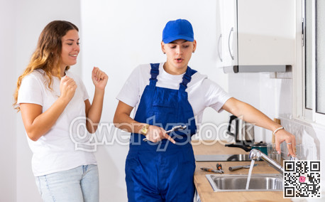 Happy satisfied housewife checks operation of the water tap in the kitchen and thanks plumber
