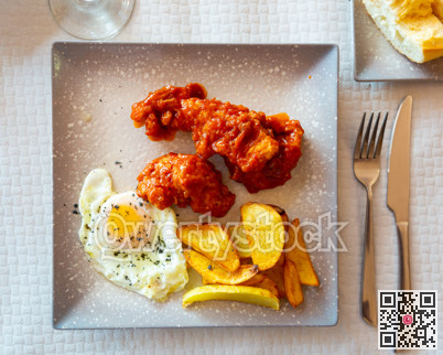 Baked potatoes with chicken in sauce and fried egg at plate