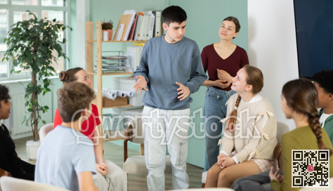 Teenage boy stands in a circle in front of other schoolchildren with a speech.