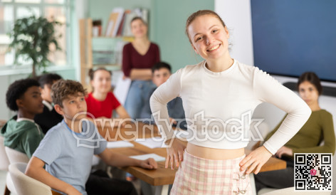 Joyful teenage girl standing in classroom