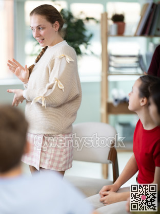 Teenage girl stands in a circle in front of other schoolchildren