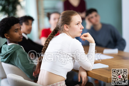 Schoolchildren teenagers sit at the table and carefully watch documentaries