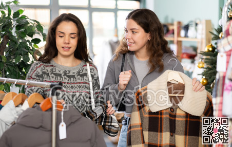 Young girls choosing coat or jacket in clothing store during Christmas