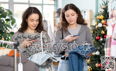 Attentive young girls scanning QR-code on jeans pantaloons in clothing store during Christmas
