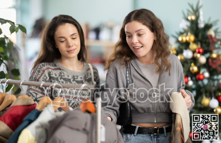 Two young women choosing coat and jacket