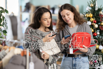 Two women with mobile phone in their hands scanning bag barcode