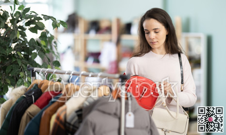 Woman carefully choosing a stylish bag in the store
