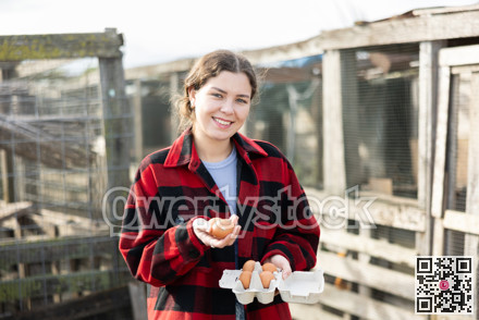 Young woman with chicken eggs in hen house