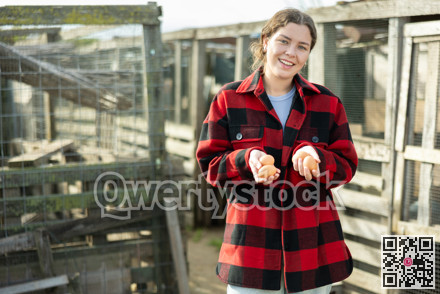 Young woman holding fresh eggs in chicken coop