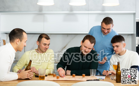 Friends drinking beer and enthusiastically playing board game at home