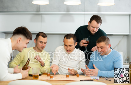 Group of cheerful men engaged in alcohol-fueled board game