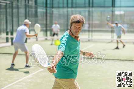 Adult and elderly men playing padel against two men
