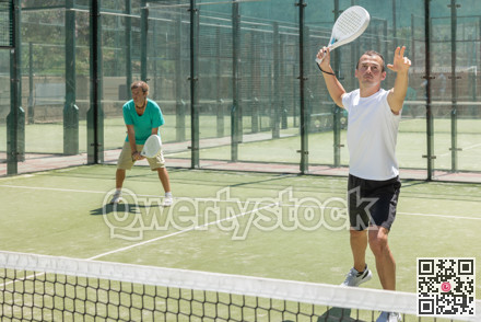 Young and adult men playing doubles padel