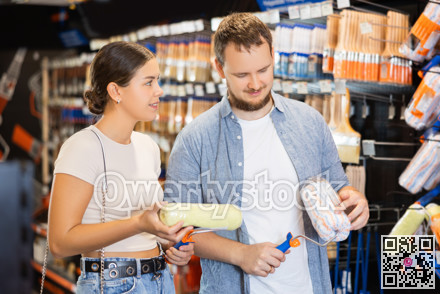 Married couple choose paint brush and paint roller together for their home renovation at hardware store