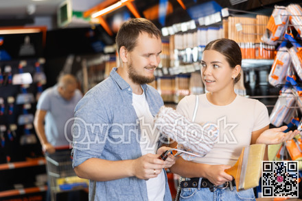 Couple man and woman choosing paint rollers and brushes