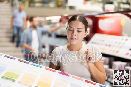 Girl examines palette, chooses color of paint for interior work in store