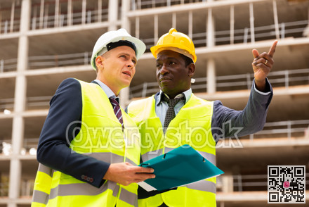 African-american engineer discussing a construction plan with a colleague shows him something
