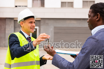 Young smiling contractor hands the keys to a man customer
