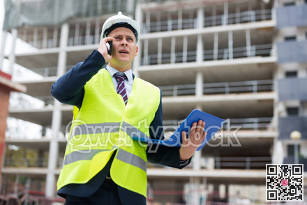 Young engineer, controlling the progress of work on a laptop, talking on a mobile phone