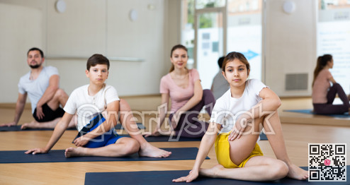 Family of four practicing yoga at gym