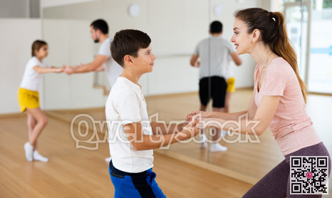 Young boy dancing waltz with his mother in gym