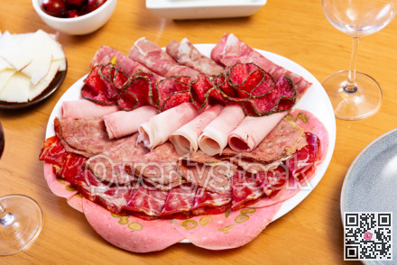 Slices of butifarra and smoked sausage dished up in a service plate on laid restaurant table