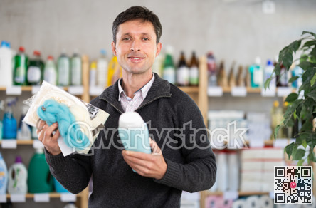 Middle-aged man holding shower gel choosing body washcloth at department store