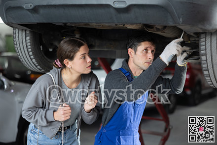 Girl watches as a professional mechanic repairs her car at car service center