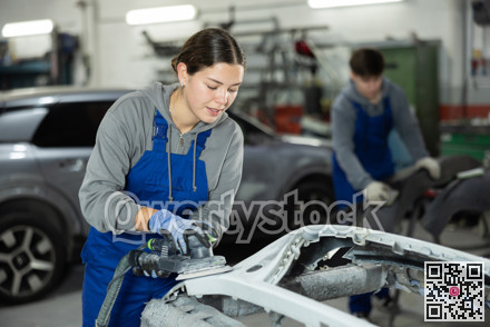 Young woman auto mechanic polishes body parts by car buffer polisher machine tool