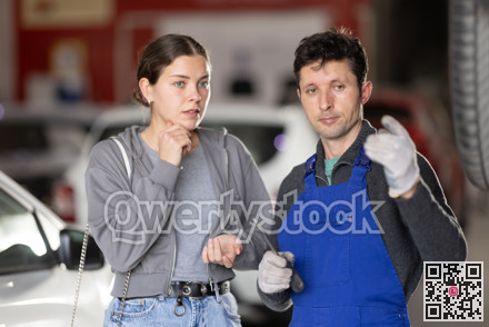 Male auto mechanic discussing with woman the cost and time to repair her car at car service