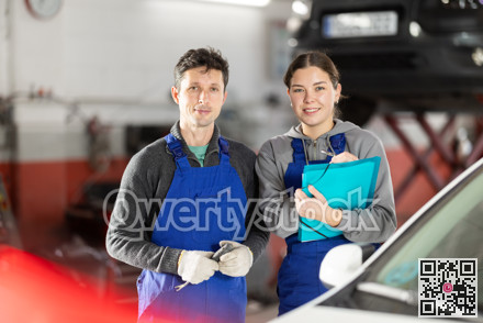 Young woman supervisor manager of car repair station with papers listens to male master