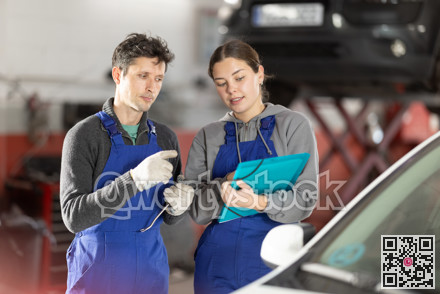 Car service manager discusses car repair problems with mechanic. He takes notes on paper