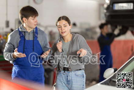 Male mechanic advises woman client on repairing of car in car service station