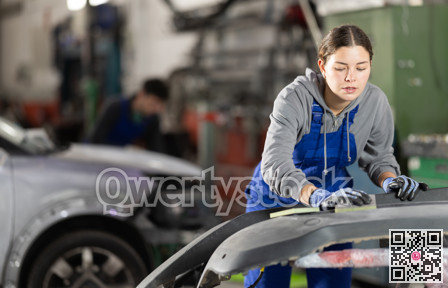 Woman car mechanic polishes car bumper - prepares bumper for painting in car service