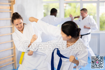Karate with two female athletes practicing, training and sparring in fight class. Healthy, fit and active women in uniform learning self defense for safety