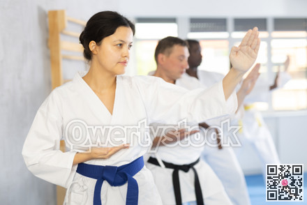 Multinational students repeat position and perform sequence of punches and painful techniques kata