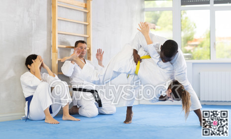 Middle-aged man applying throwing technique on his opponent in sports hall
