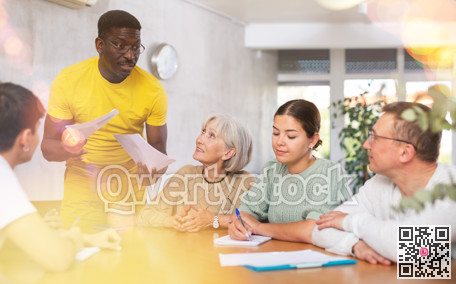 Experienced male coach conducts training for people of different nationalities in classroom