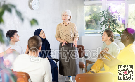 Mature female teacher giving lecture to group of multinational students